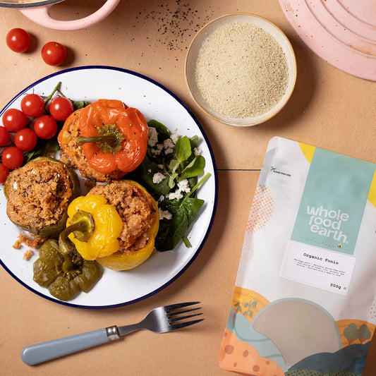 Organic Whole Food Earth Fonio grains in a rustic bowl with fresh herbs on a wooden table, highlighting natural cereal and rice product.