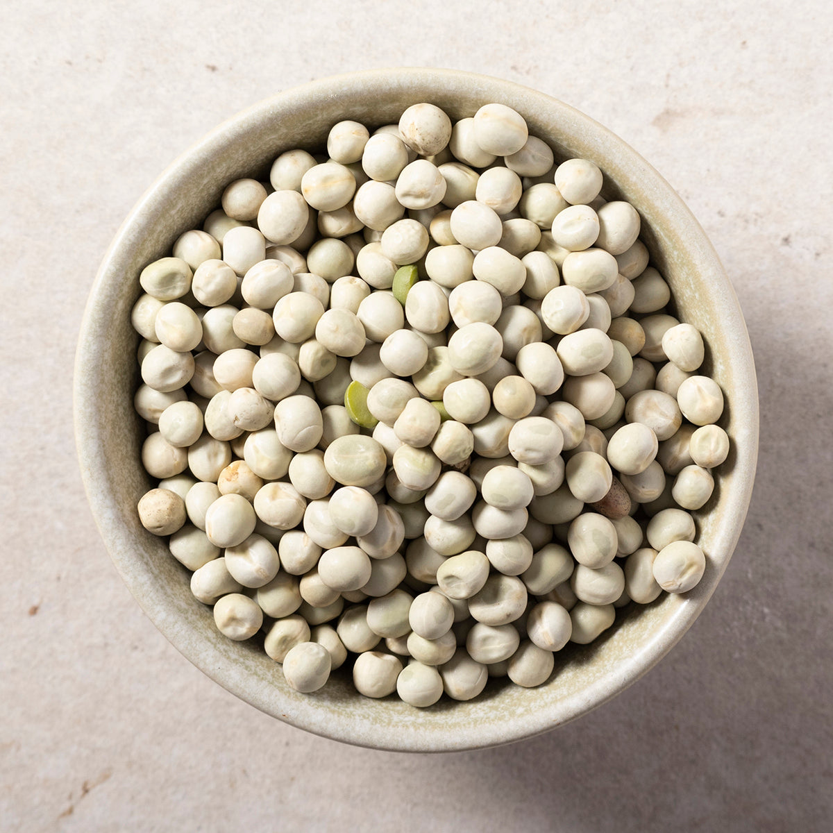 Organic green peas from Whole Food Earth, fresh and vibrant, shown in a bowl with some peas spilling out on a white background.