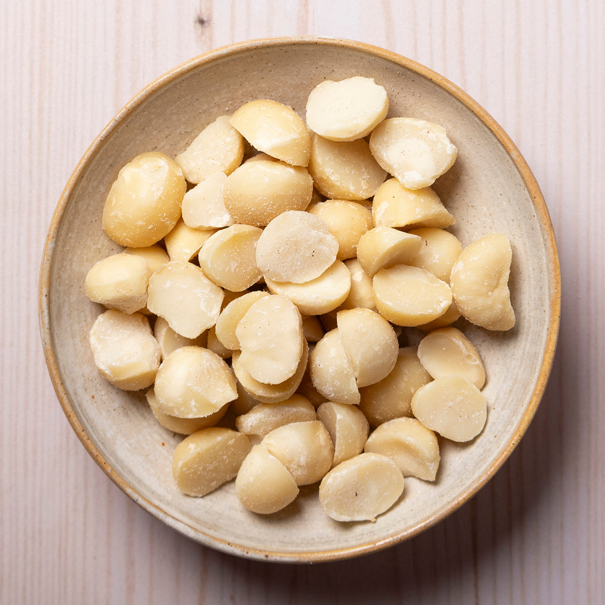 Organic Whole Food Earth macadamia nuts in a bowl, showcasing their creamy, crunchy texture and natural brown shells.