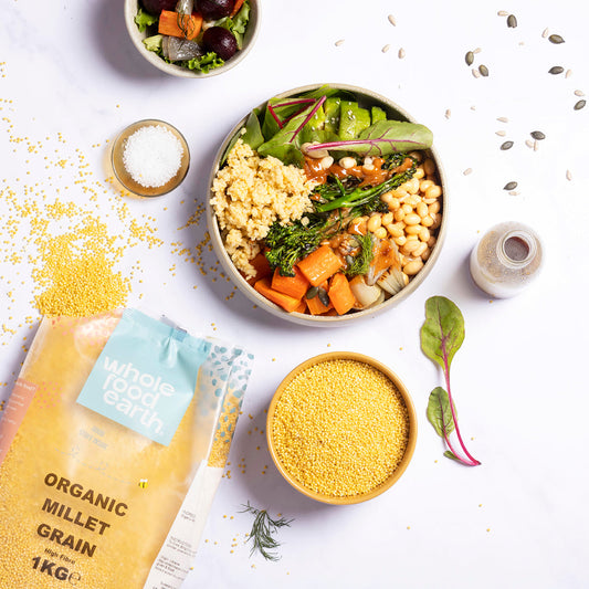 Organic millet grain from Whole Food Earth, displayed in a natural setting with a bowl of cooked millet and millet grains spread out.