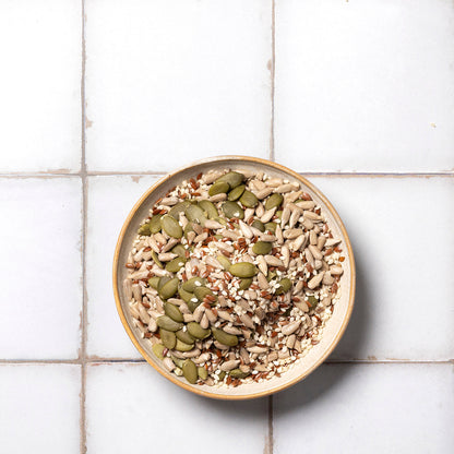 Organic Omega Seed Mix featuring a variety of nutritious seeds, including flax, chia, sunflower, and pumpkin seeds, in a clear bowl.
