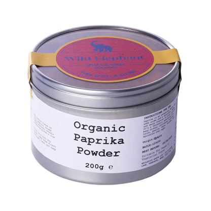 Organic paprika powder from Wild Elephant, a vibrant red herb and spice, in a clear glass jar on a white background.