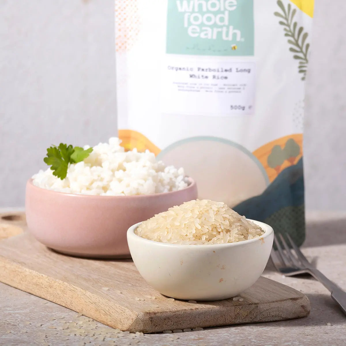 Organic Whole Food Earth parboiled long white rice in a bowl with grains and cooking ingredients on a kitchen counter.
