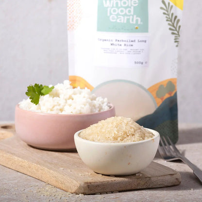 Organic Whole Food Earth parboiled long white rice in a bowl with grains and cooking ingredients on a kitchen counter.