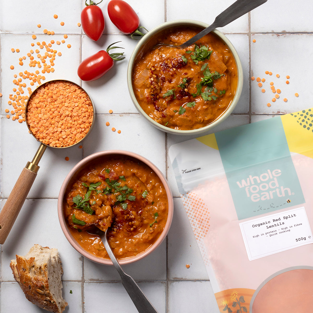 Organic red split lentils from Whole Food Earth, shown in a bowl with fresh vegetables on a rustic wooden table.