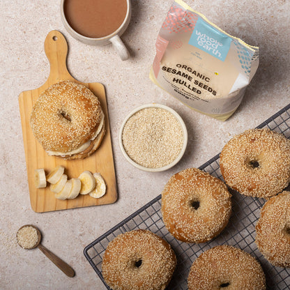 Organic hulled sesame seeds from Whole Food Earth displayed in a glass jar with a spoon on a rustic wooden background.