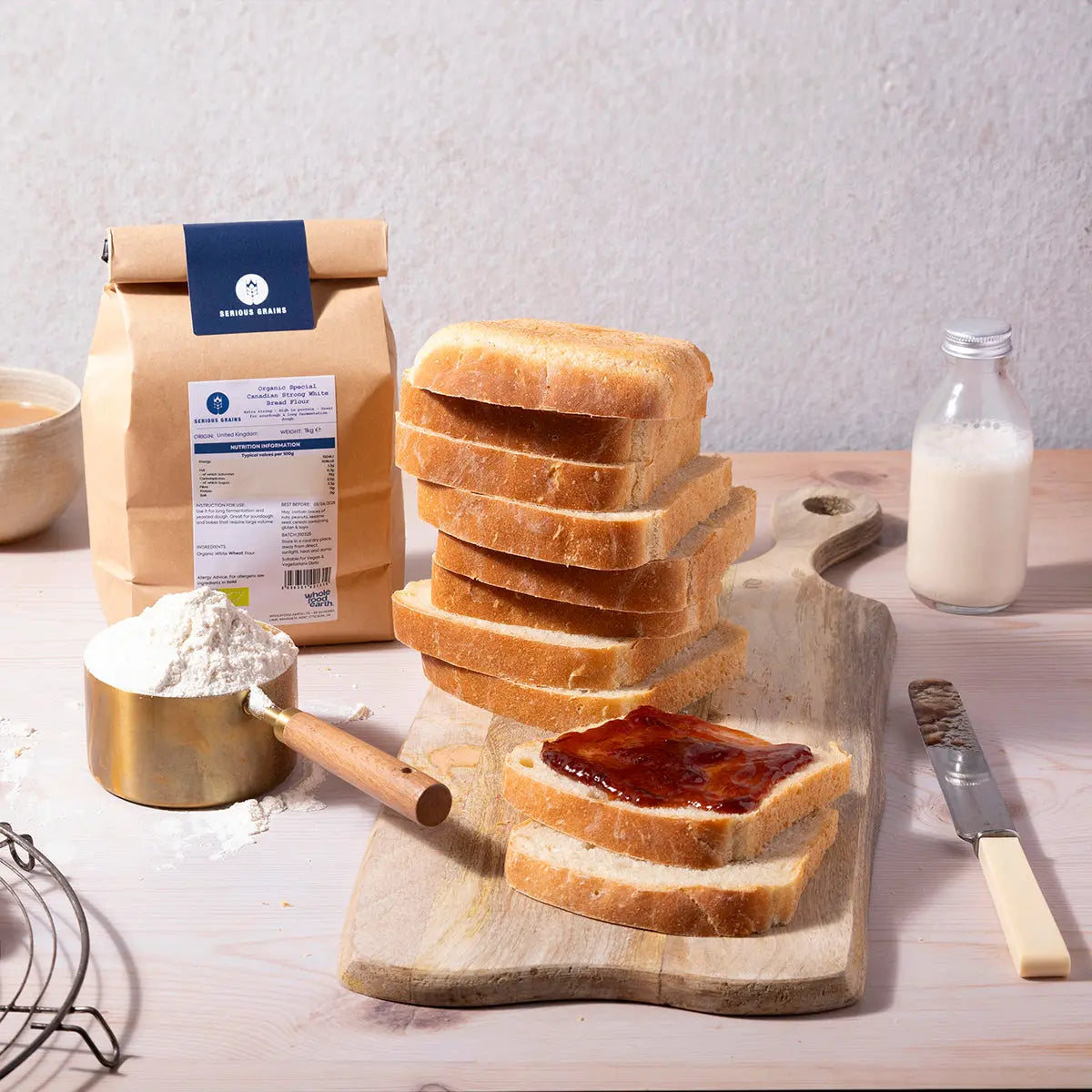 Organic Canadian strong white bread flour by Whole Food Earth, shown in a kitchen setting with baking ingredients and dough.