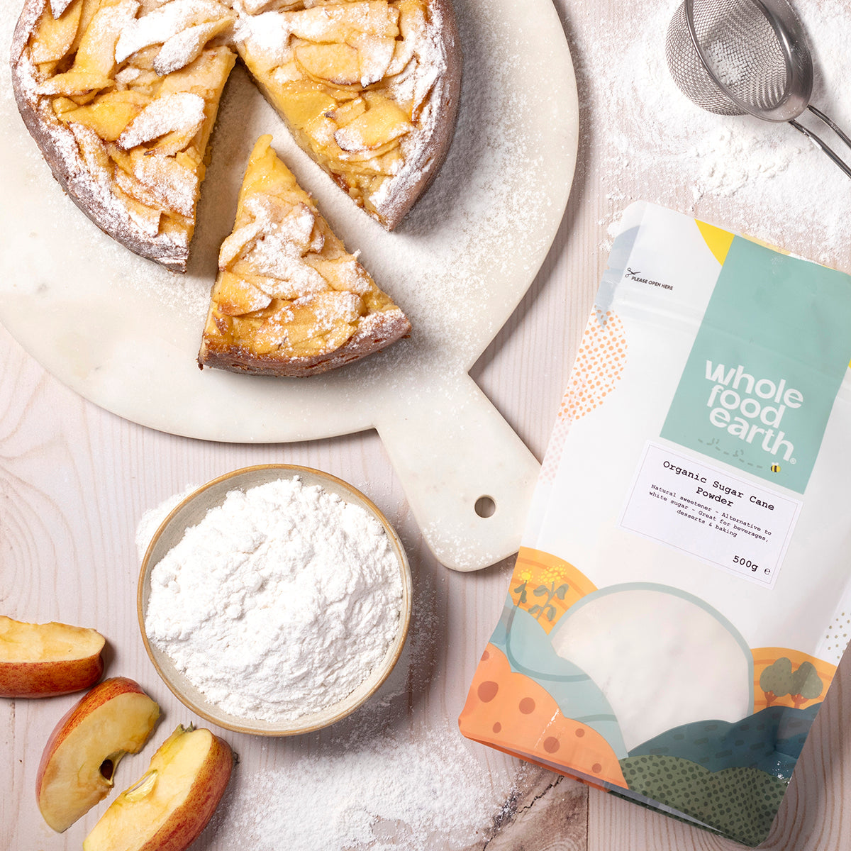 Organic sugar cane powder from Whole Food Earth, displayed on a wooden table with a spoon and fresh ingredients for natural sweetness.
