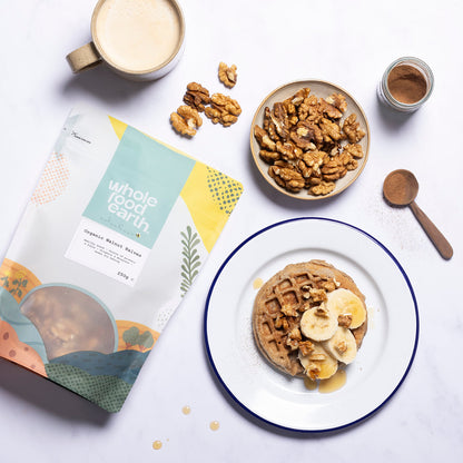 Organic Walnut Halves from Whole Food Earth, displayed in a bowl with scattered walnut pieces on a rustic wooden surface.