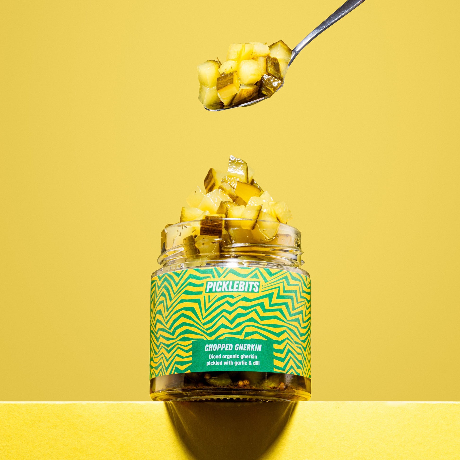 Organic chopped dill pickles in a jar by PICKLEBITS, showcasing vibrant green gherkin pieces with visible dill seasoning.
