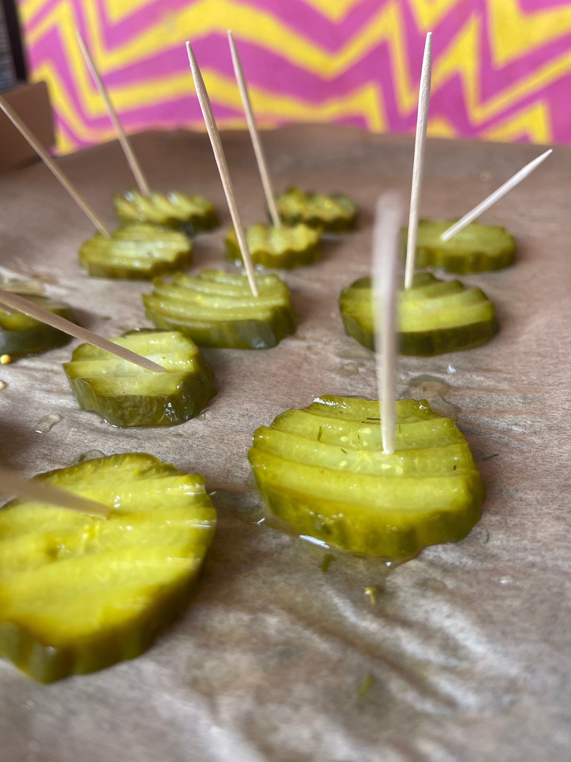 Thick-cut organic dill and garlic pickle slices from PICKLEBITS, shown in a clear glass jar with vibrant green pickles.