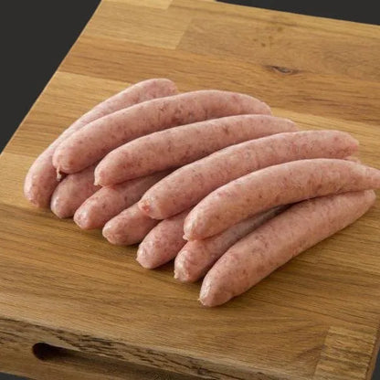 Primrose Herd chipolata sausages, raw and uncooked, shown in black background, ready for cooking or grilling.
