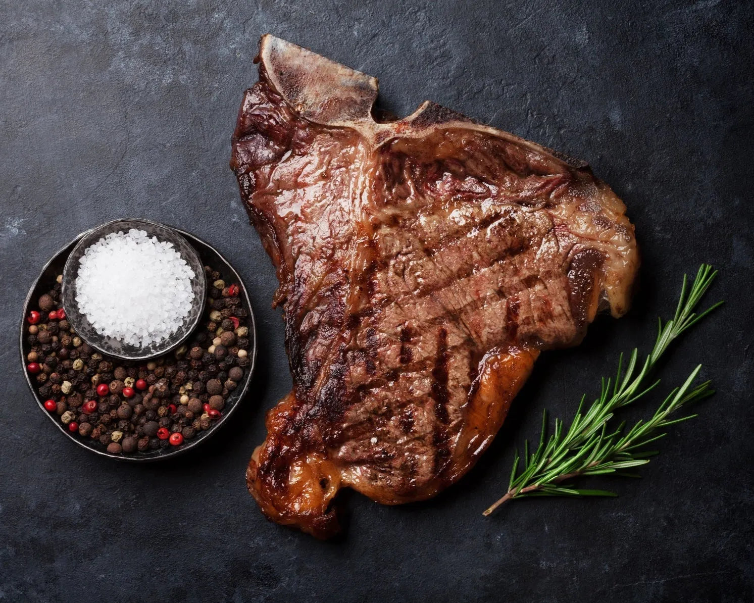 Prime dry-aged T-bone beef steak from Primrose Herd, showcasing marbled beef with a T-shaped bone and rich, aged surface.