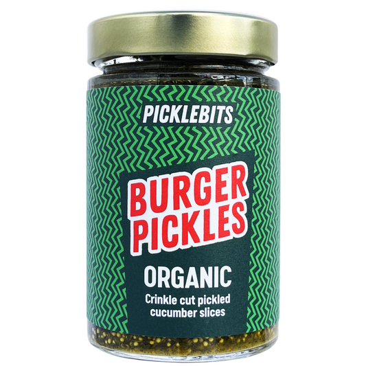 Organic burger pickles from PICKLEBITS, featuring dill and garlic, shown in a jar with fresh, sliced pickles ready for a burger.