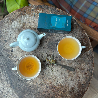 A cup of PekoeTea Edinburgh Summer Fruits tea with fresh summer fruits and tea leaves in a bright, inviting setting