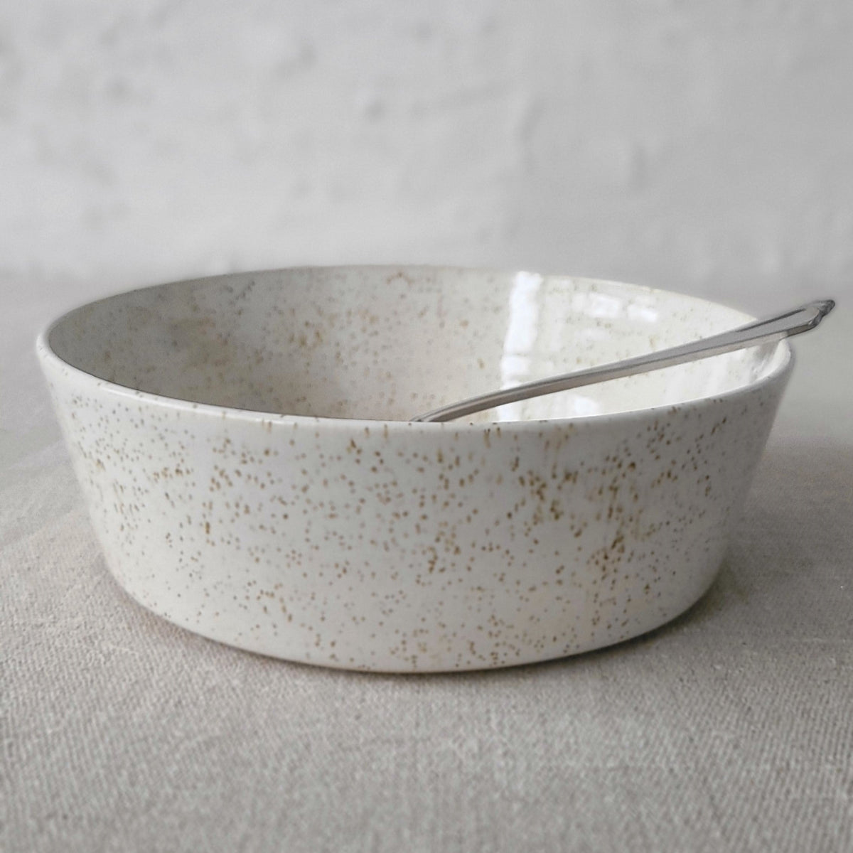 White ceramic Pepper White Classic Pasta Bowl by Katie L Thompson Designs with matching spoon on a neutral background.