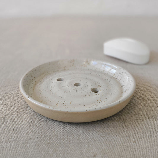 Katie L Thompson Designs Pepper White Classic Soap Dish holding a bar of soap on a bathroom countertop.