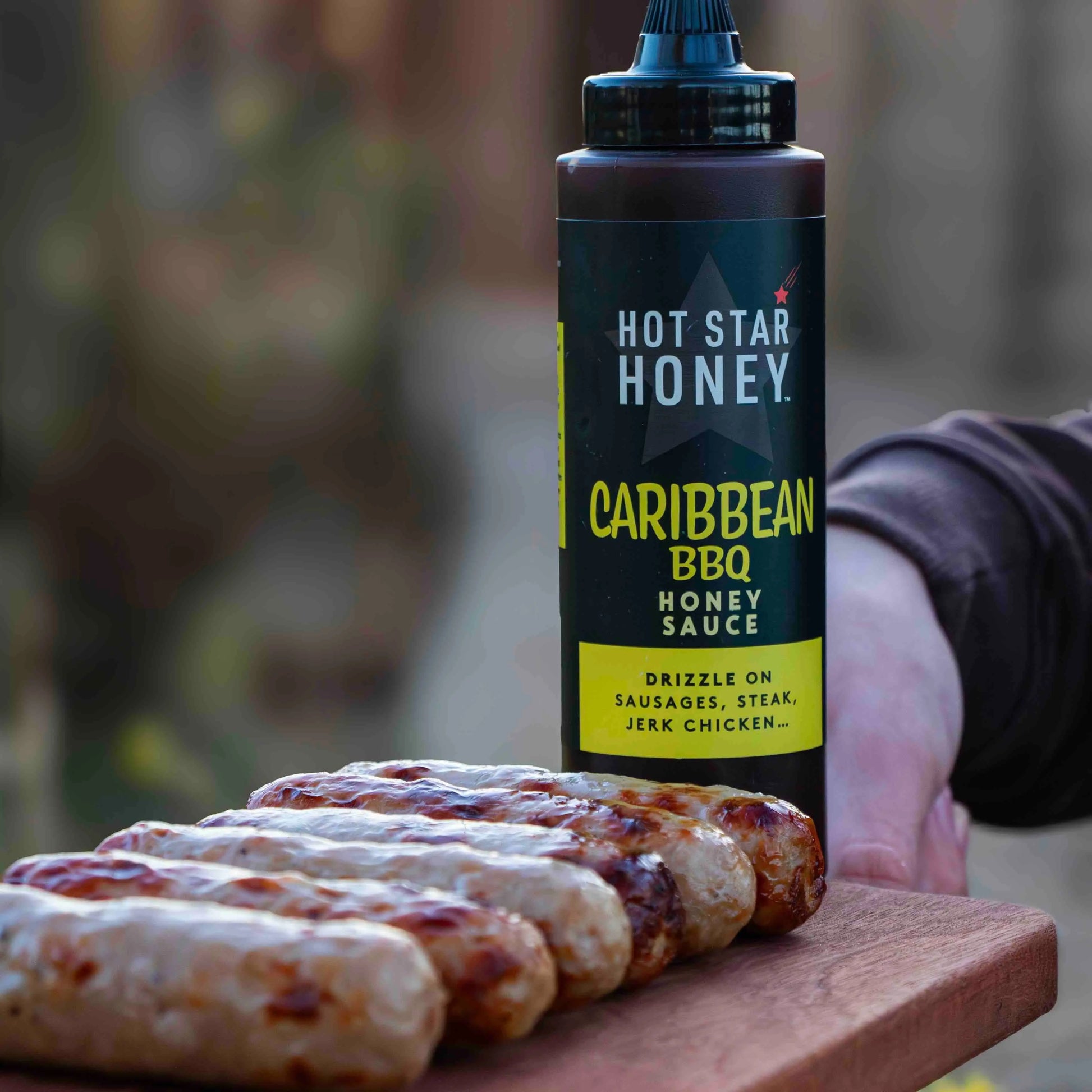 Hot Star Honey Caribbean BBQ sauce poured over grilled sausage, showcasing the glossy, flavorful honey-infused barbecue sauce.
