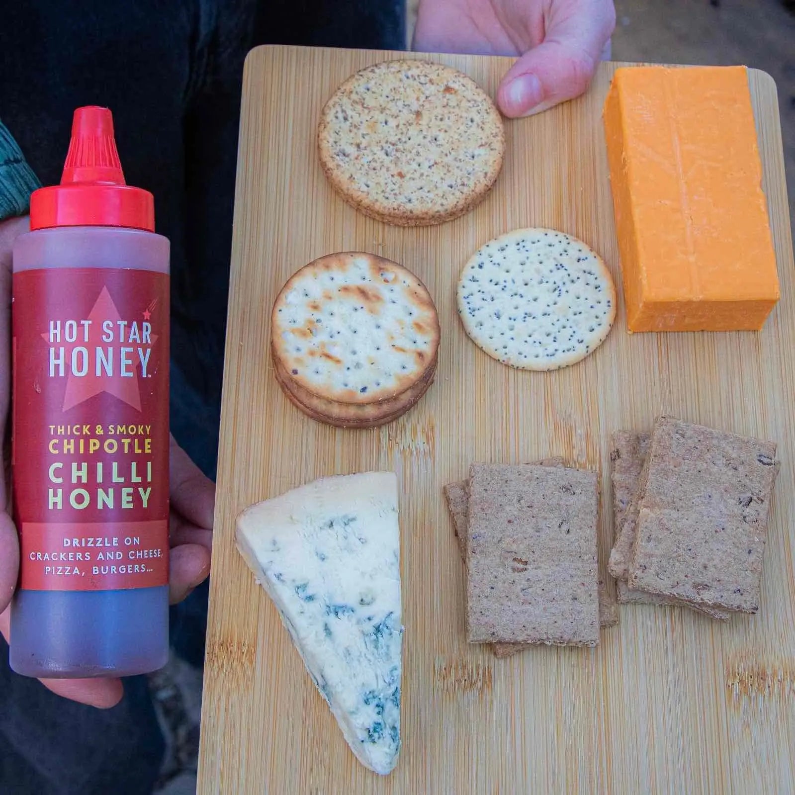 Hot Star Honey Chipotle Chilli Honey drizzled on cheese and crackers, showcasing its spicy, sweet flavor and vibrant amber color.