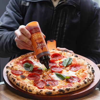 Spicy chili honey with habanero peppers drizzled on a pizza, showcasing the Hot Star Honey Chilli Honey product.