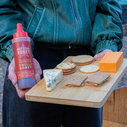 Chipotle chili honey drizzled on cheese and crackers, showcasing Hot Star Honey's spicy sweet chili honey product.