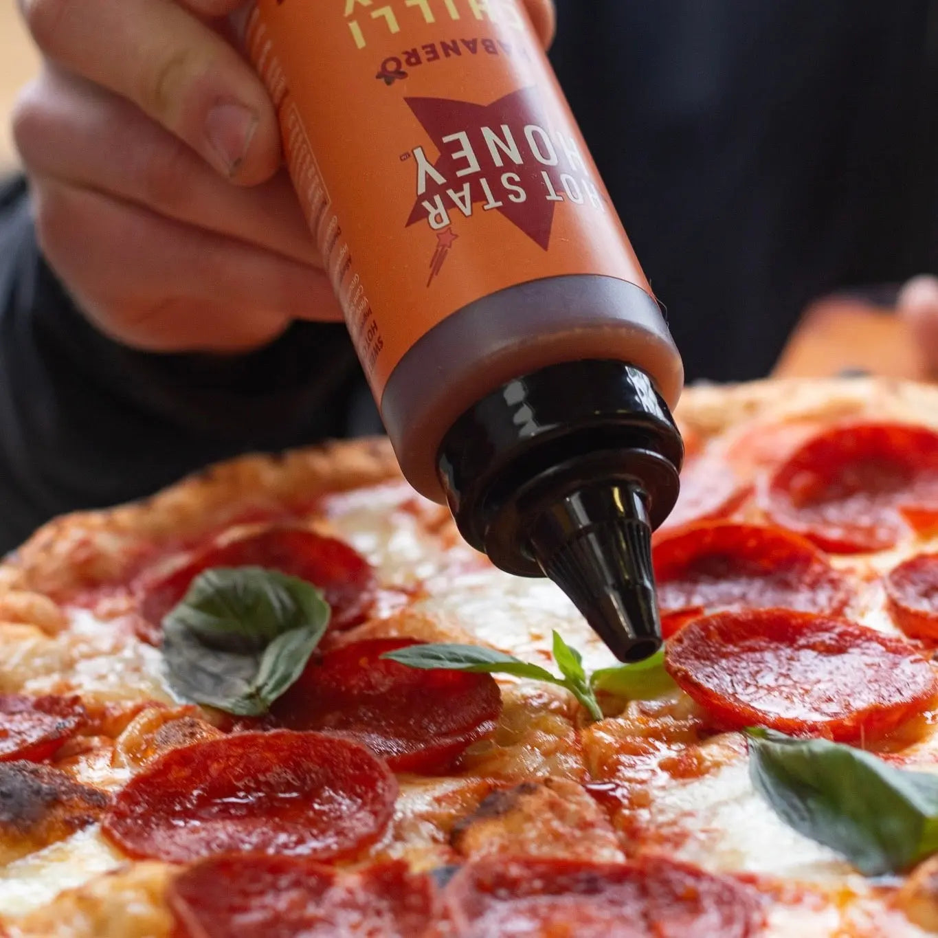 Spicy habanero hot chili honey drizzle on pizza, showcasing vibrant orange honey with sliced habanero peppers.
