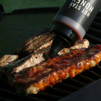 Hot Star Honey Caribbean BBQ Sauce drizzled on grilled meat, showcasing its rich, sweet, and smoky flavor.