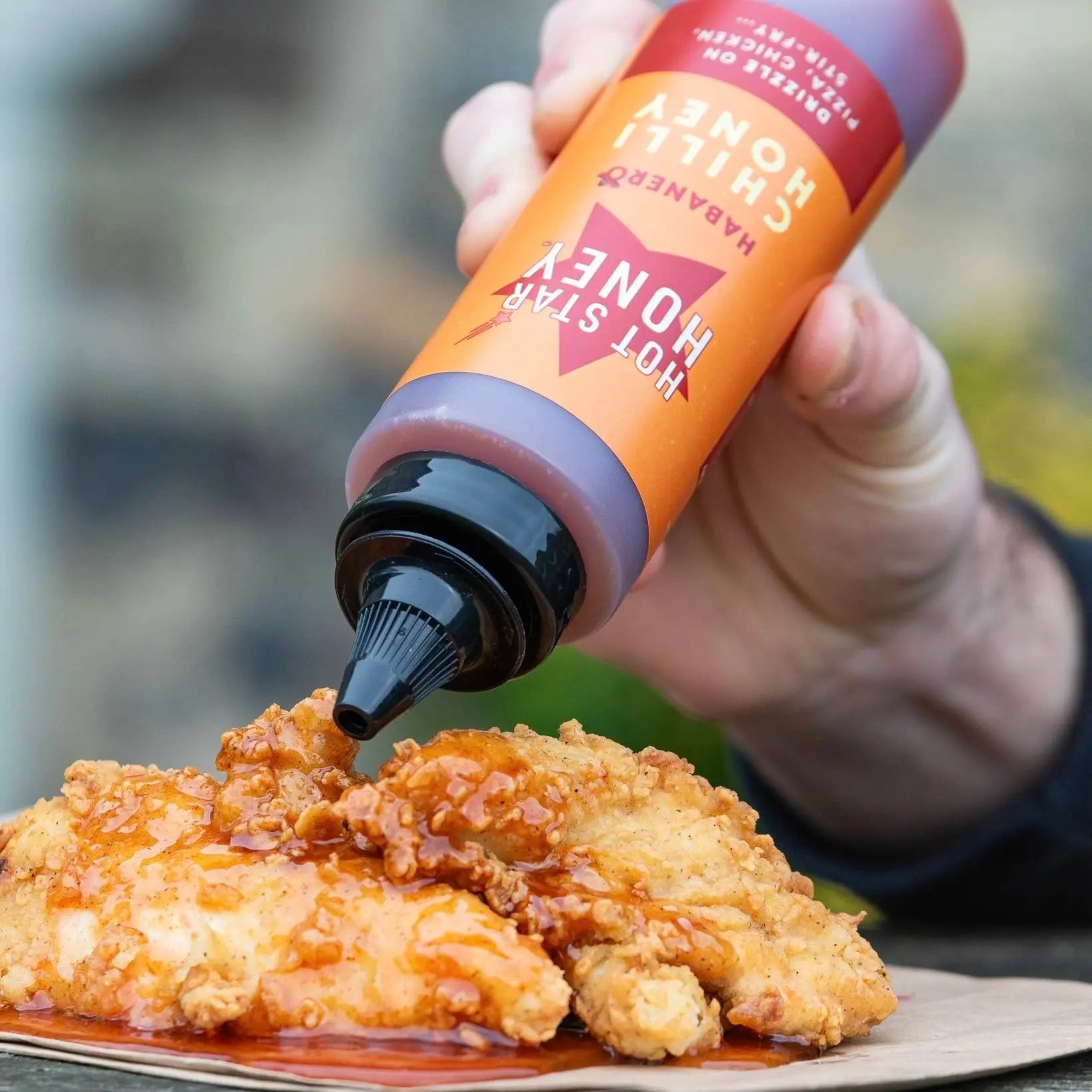 Spicy habanero chili honey drizzled on grilled chicken, showcasing the bright orange chili and glossy honey texture.