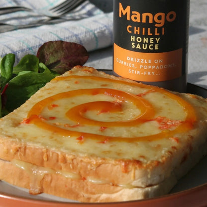 Asian-inspired Mango Chilli Honey Sauce drizzled on toast, showcasing vibrant mango slices and spicy chili flavor by Hot Star Honey.