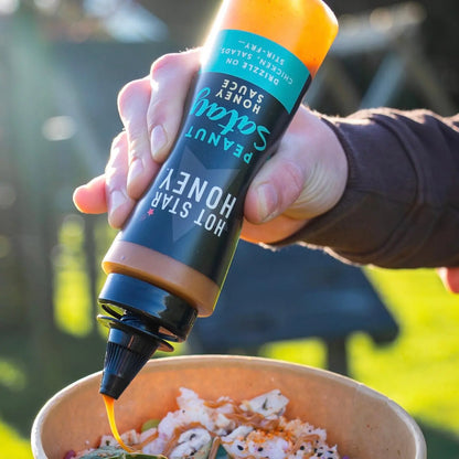 Asian-inspired Peanut Satay Honey Sauce by Hot Star Honey drizzled over a dish with peanuts and herbs.