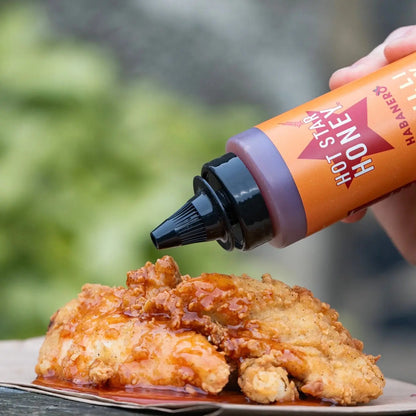 Spicy habanero chili honey drizzled over grilled chicken, showcasing the Hot Star Honey brand and vibrant chili peppers.
