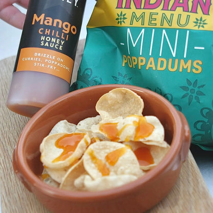 Asian-inspired Mango Chilli Honey Sauce from Hot Star Honey served on crispy popadoms with mango slices and chili peppers.
