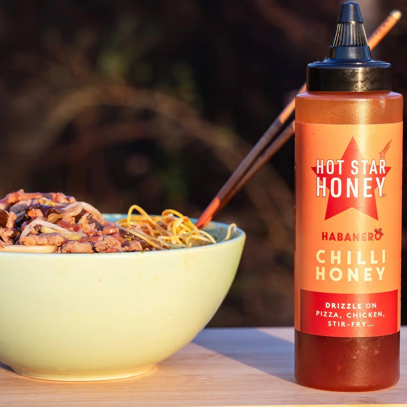 Habanero hot chili honey from Hot Star Honey drizzled over stir-fry with visible habanero peppers and glossy honey.