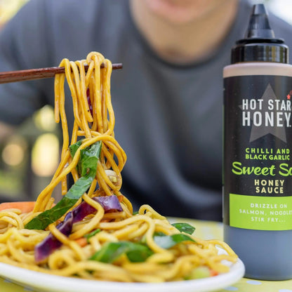 Asian-inspired sweet soy sauce with chili and black garlic by Hot Star Honey, shown drizzled over a stir-fry dish.