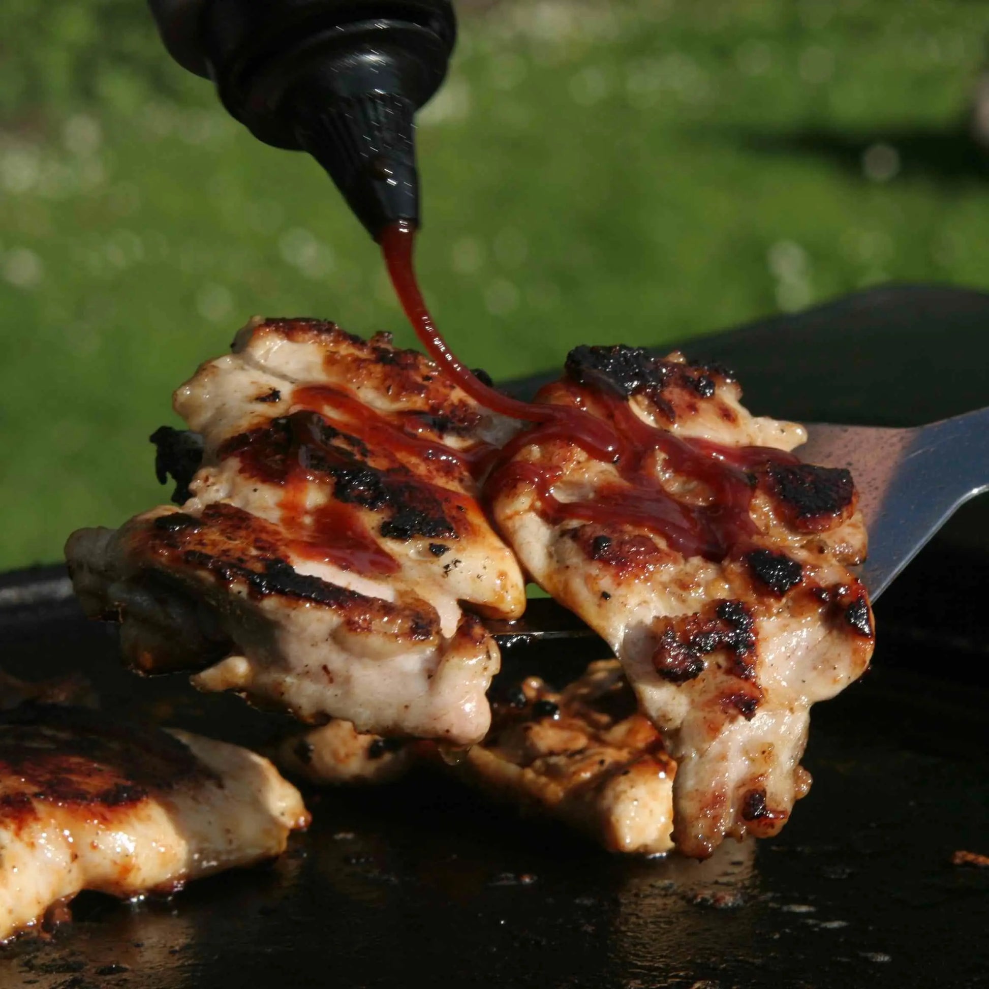 Hot Star Honey Caribbean BBQ sauce poured over grilled chicken, showcasing a glossy, flavorful barbecue glaze.