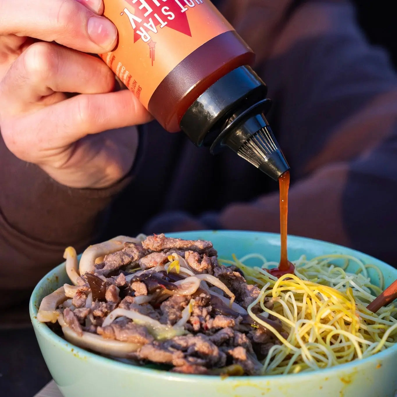 Hot Star Honey habanero chili honey drizzled on stir-fry, showcasing spicy, golden chili honey with fresh habanero peppers.