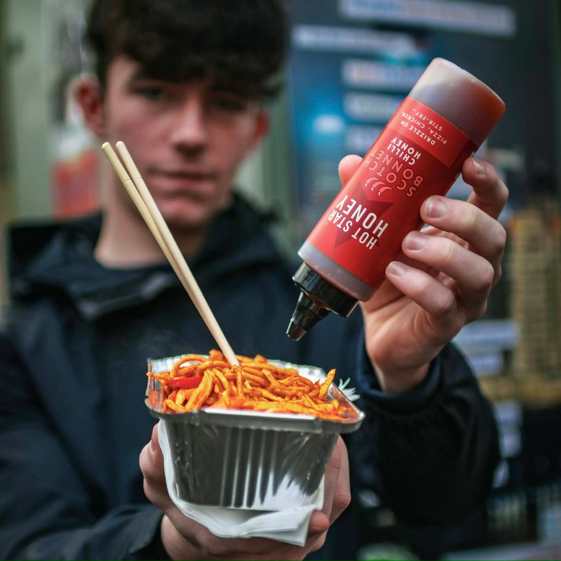 Spicy Scotch Bonnet chilli honey from Hot Star Honey drizzled over a stir-fry dish with vegetables and meat.