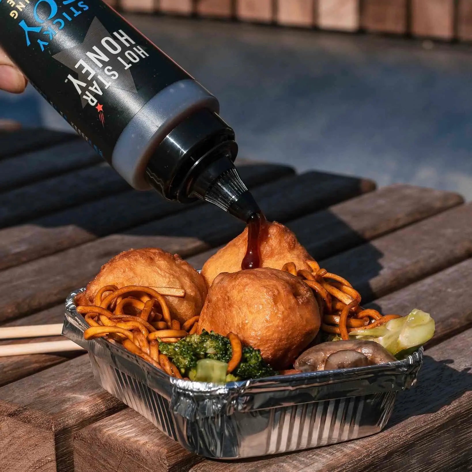 Asian-inspired sticky soy dipping sauce by Hot Star Honey served in a small dish with chopsticks on a wooden table.