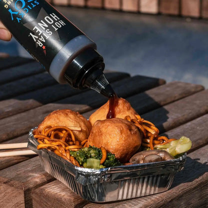 Asian-inspired sticky soy dipping sauce by Hot Star Honey served in a small dish with chopsticks on a wooden table.