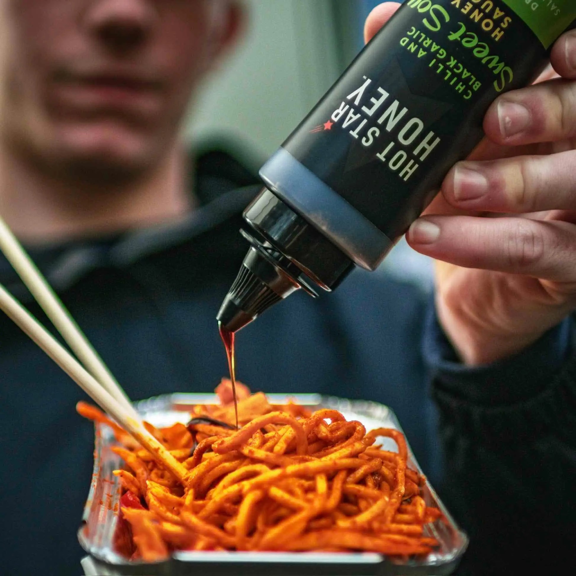 Asian inspired sweet soy sauce with chili and black garlic drizzled over noodles in a bowl.
