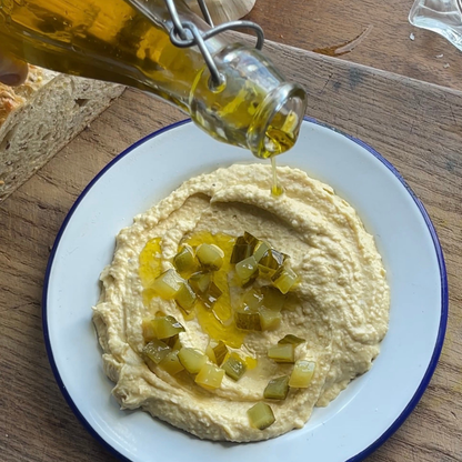 Organic chopped dill pickles in a jar, featured alongside hummus, showcasing PICKLEBITS' fresh, flavorful pickled vegetables.