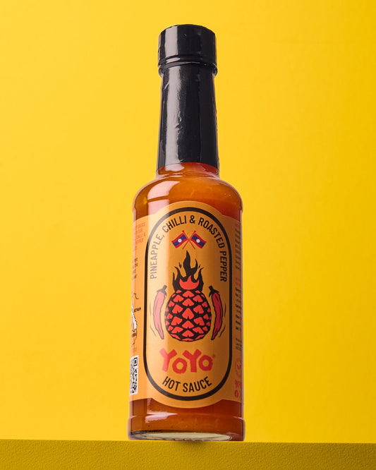 YoYo Laos Sauce pineapple chili and roasted pepper signature sauce bottle with vibrant label and fresh ingredients.