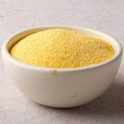 Whole Food Earth polenta, yellow cornmeal grain flour, close-up view of textured, uncooked polenta for cooking or baking.