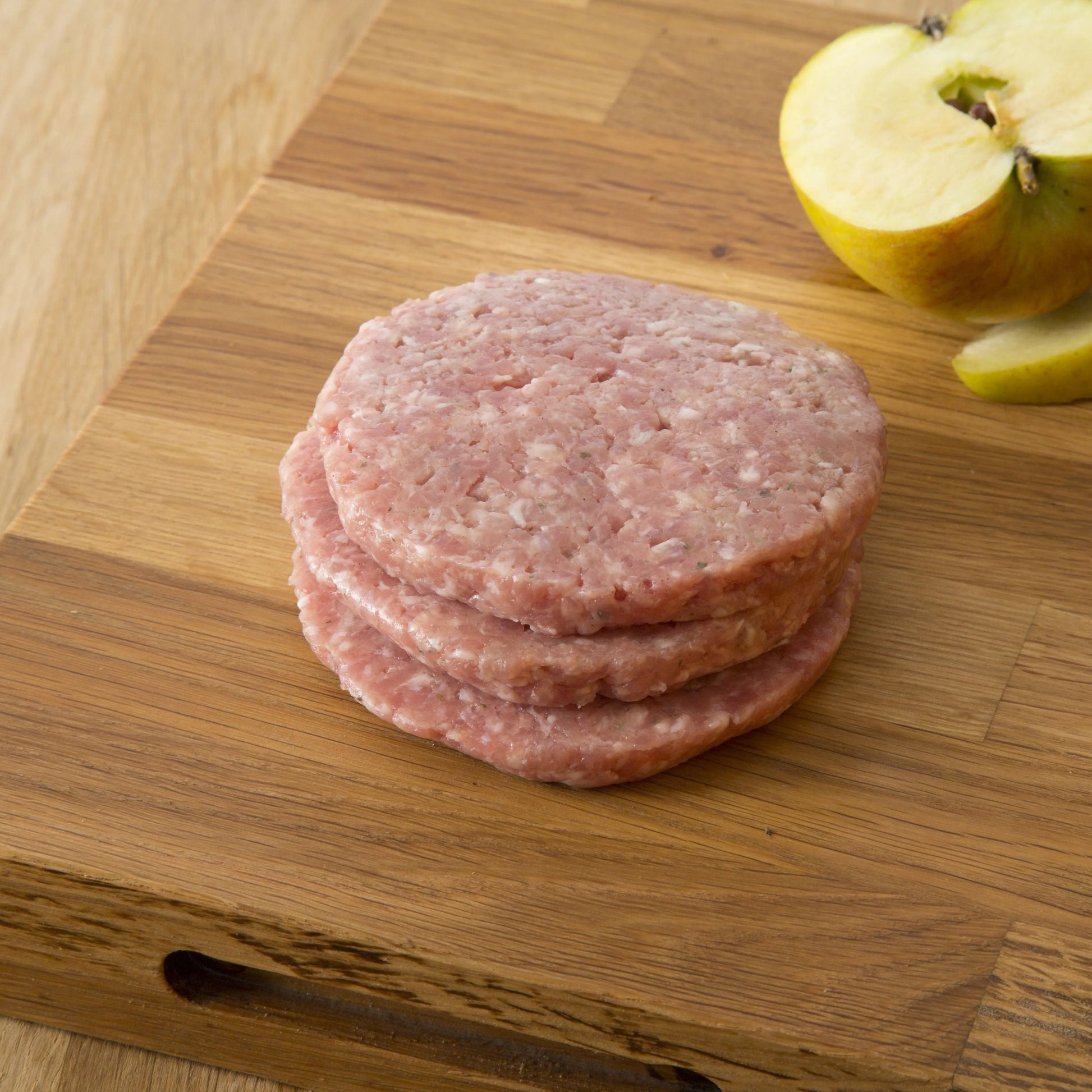 Primrose Herd pork and apple burgers with seasoned pork patties topped with fresh apple slices on a bun.