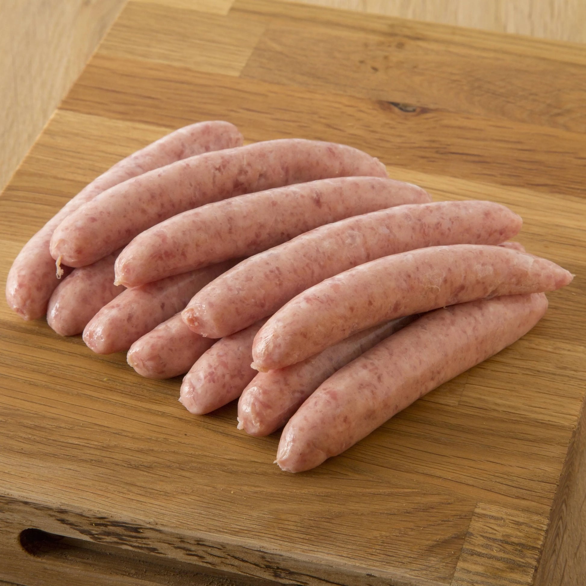 Primrose Herd chipolata sausage variety pack with freshly cooked pork chipolatas on a plate, showcasing the sausages' golden-brown appearance.