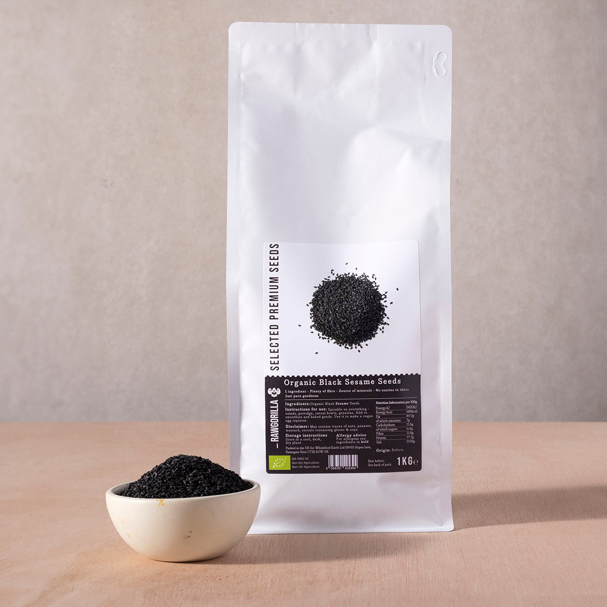 Organic black sesame seeds in a clear container, showcasing small black seeds from RAWGORILLA brand on a white background.