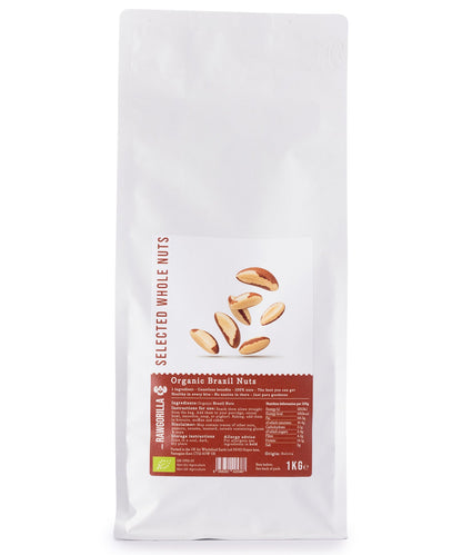 Raw organic Brazil nuts from RAWGORILLA, 1kg, displayed in a clear bowl with some nuts scattered around, on a wooden surface.