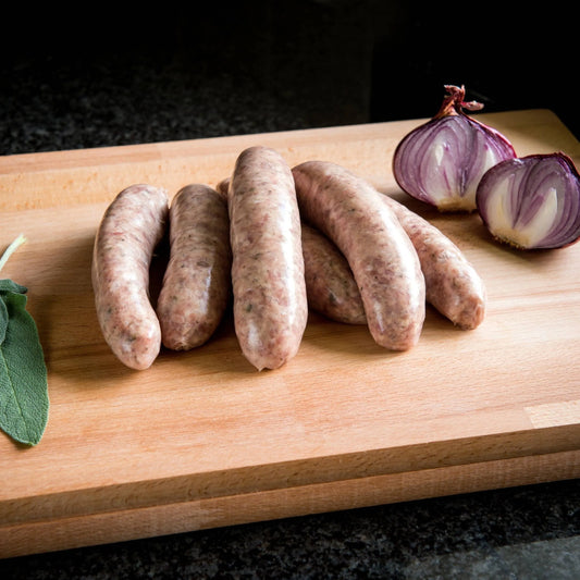 Primrose Herd Cornish Heritage Pork Sage and Red Onion Sausages 500g, raw sausages with herbs and red onion visible.