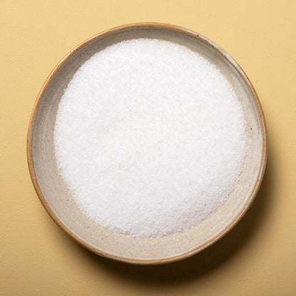 Close-up of fine sea salt from Whole Food Earth, showing white crystalline mineral salt grains on a white background.