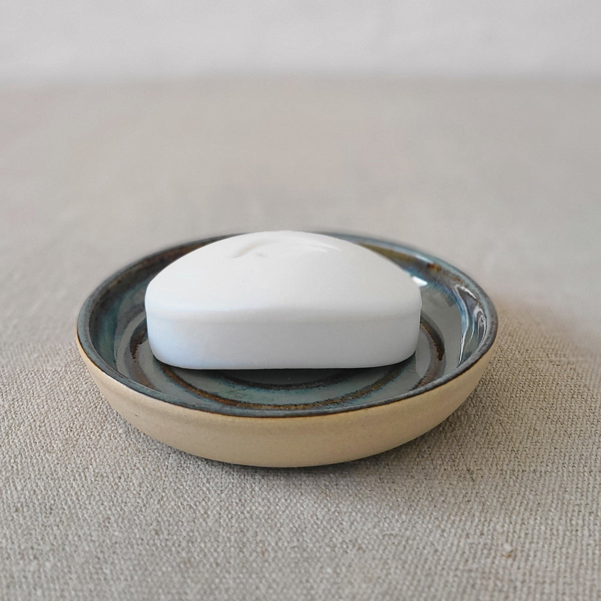 Seafoam blue ceramic soap dish with a soap bar from Katie L Thompson Designs, showcasing a smooth, glossy finish and modern design.